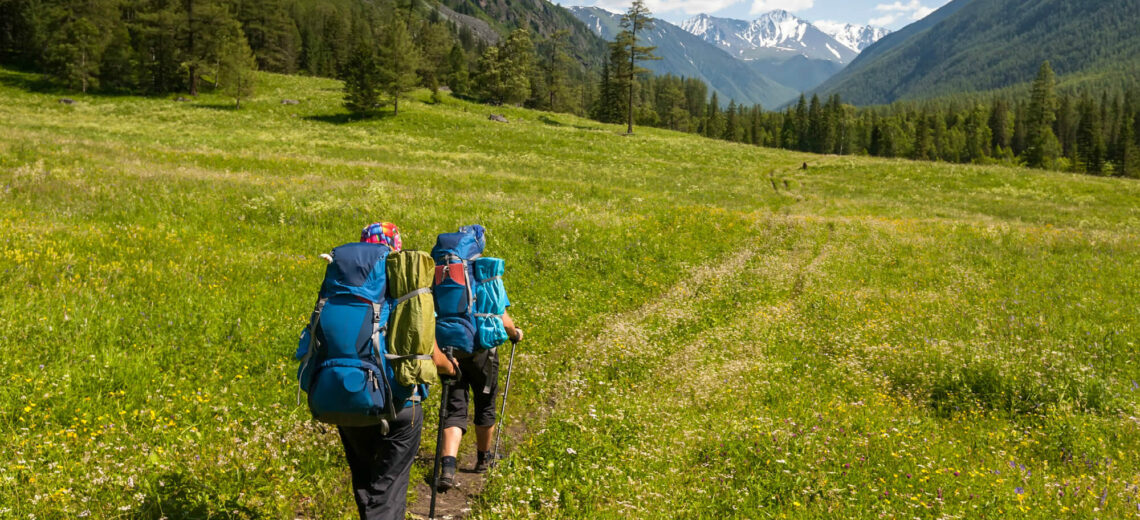 Hikers going over trails in Deer Valley Utah with full backpacks on beautiful summer mid-morning day walking towards mountain