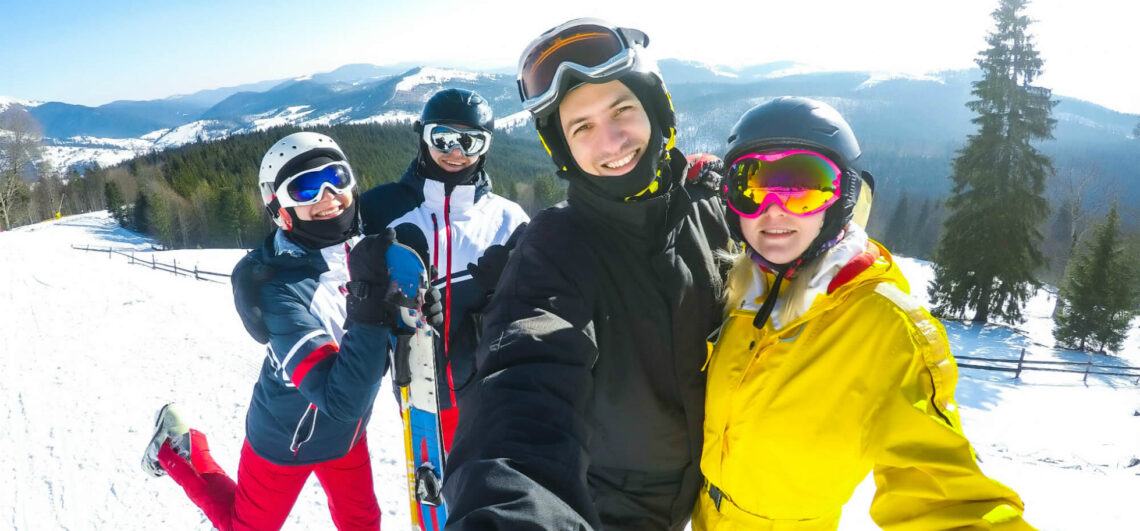 Four friends skiers stopped for selfie on top of Deer Valley Ski Run in Park City Utah